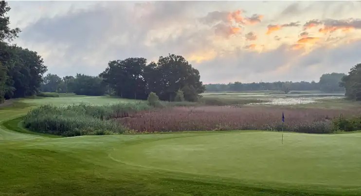 Golf course green at sunrise with marsh and trees at Turnberry